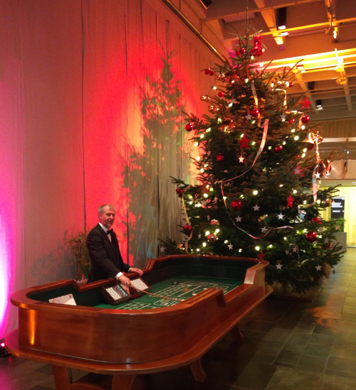 Ein Croupier steht am full-size Crapstisch, im Hintergrund ein großer, geschmückter Weihnachtsbaum